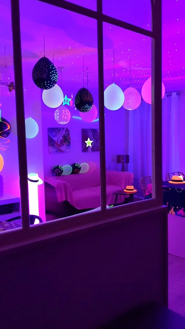 Sala con globos fluorescentes colgando del techo y sofá, vista a través de la cristalera
