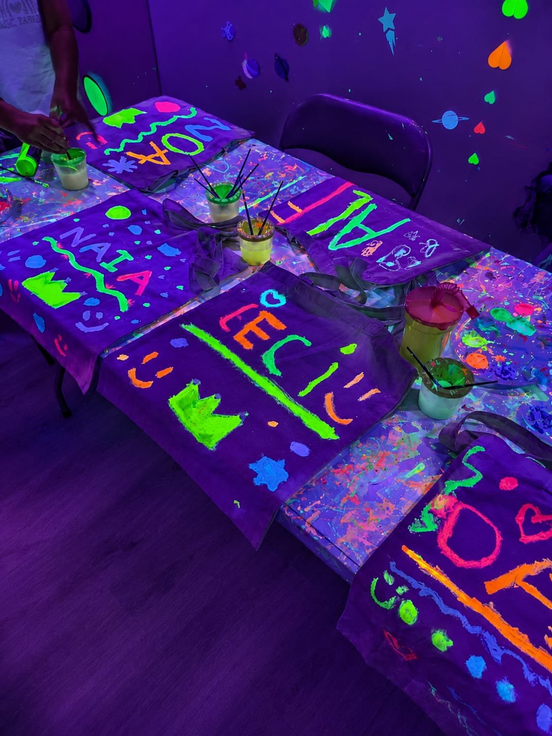 Delantales y bolsas de tela pintados con colores fluorescentes sobre la mesa del taller
