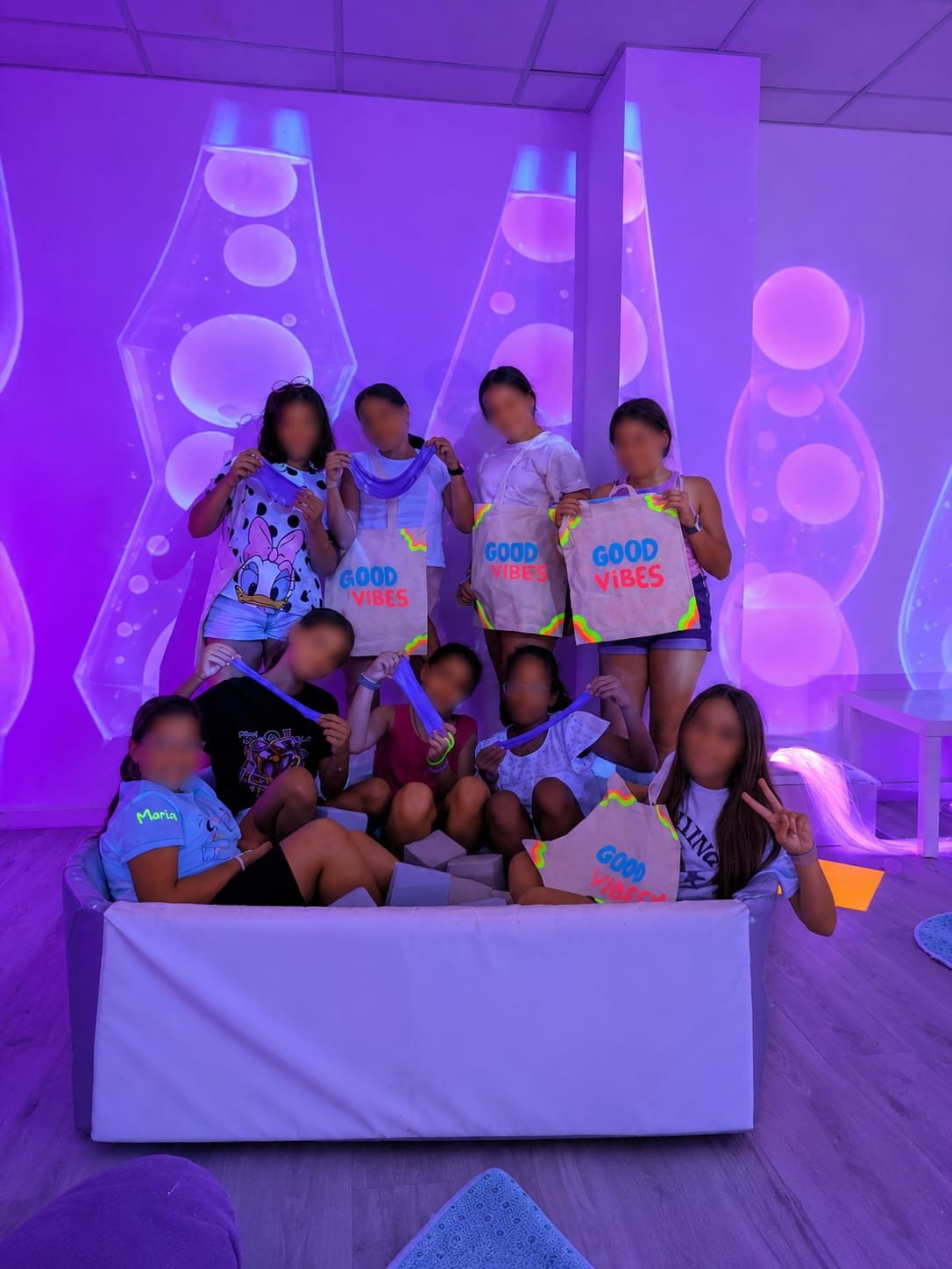Grupo de niños con bolsas de tela pintadas en la sala, delante de la proyección de lámparas de lava