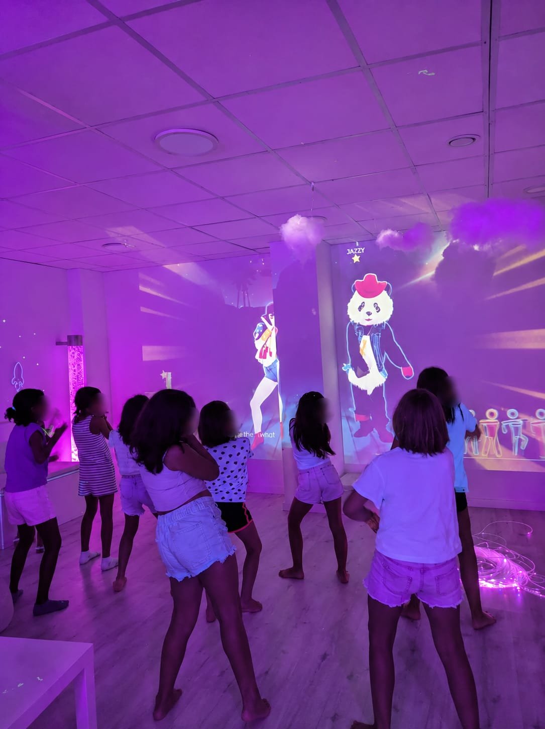 Niños bailando frente a una proyección en la pared de la sala