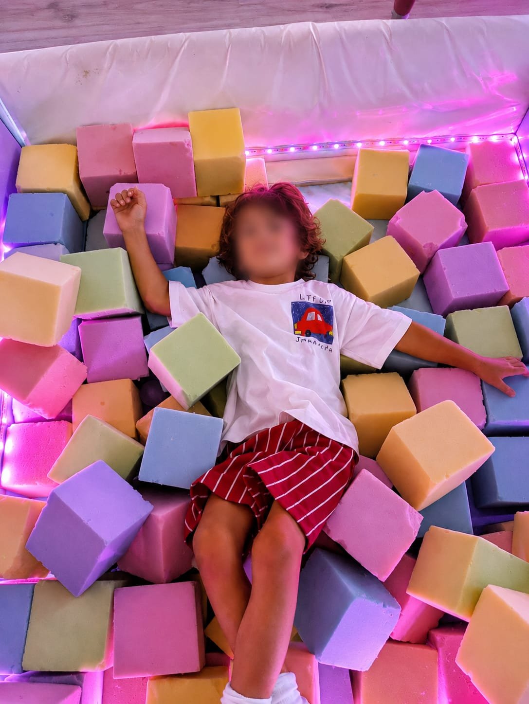 Un niño tumbado entre cubos de gomaespuma de colores en la piscina de la sala